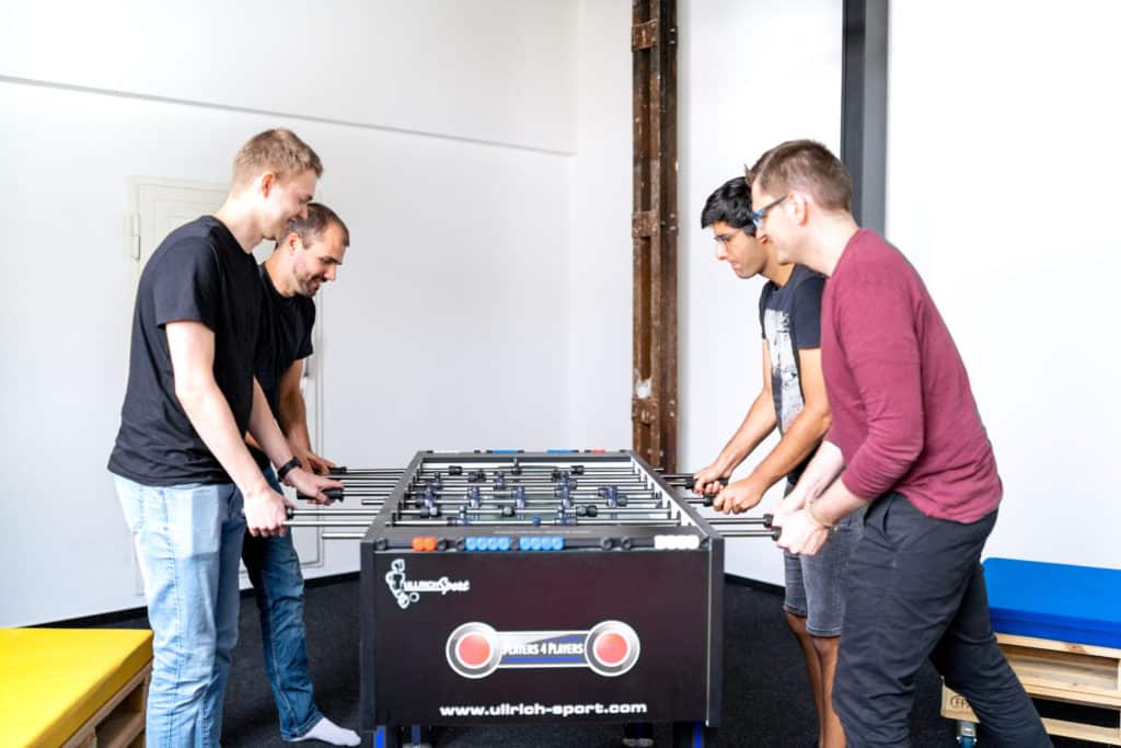 Four men playing foosball in the office